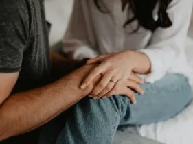 Close-up of a woman holding a man's hand, showing emotional support and connection.